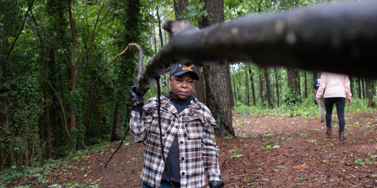 Woman carrying branch over her shoulder.