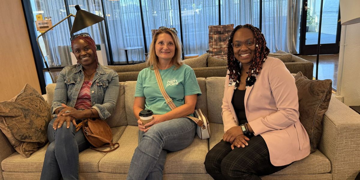 Three people sitting on a couch and smiling at the camera