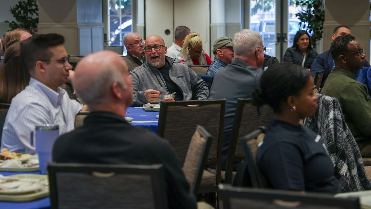 Group of people sit around table listening to presentation.