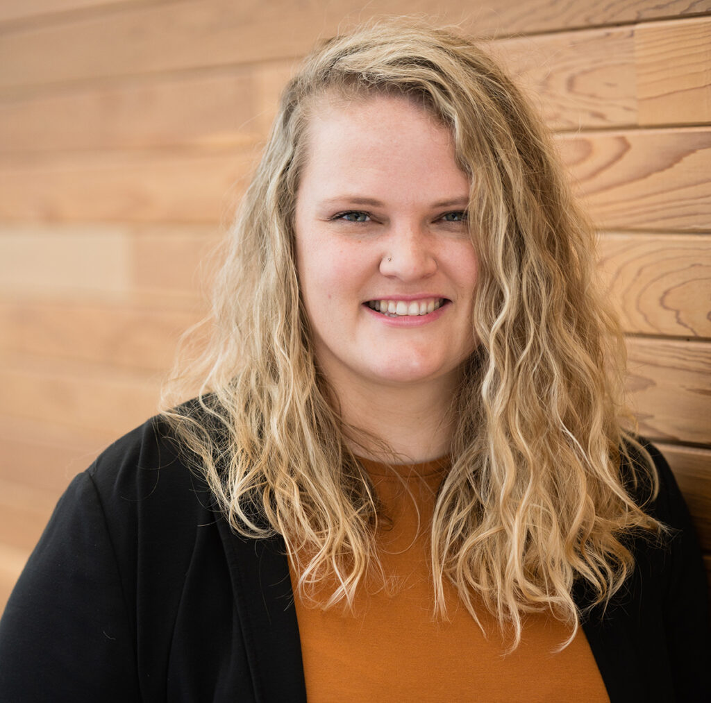 Blonde woman with curly hair smiles at the camera
